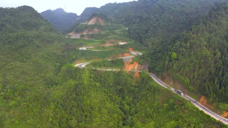 aerial shot of a winding road full of switchbacks cutting through the misty mountains of vietnam