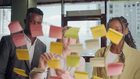 werk op kantoor drie mensen van verschillende rassen bespreken een nieuw project plakken post-it notities