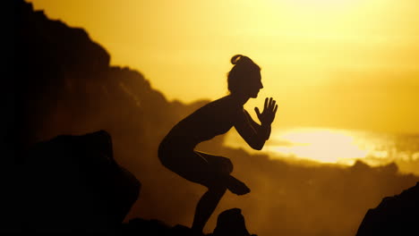 woman practicing yoga at sunset on a rocky beach
