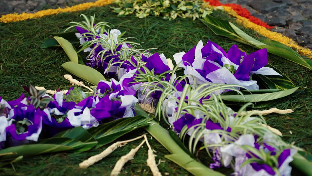 Decorative cross made of plants, flowers, and colored paper forming part of an alfombra for Semana Santa in Antigua Guatemala.
