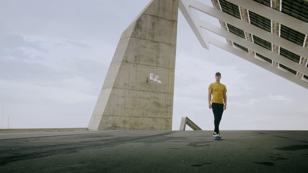 retrato épico y primer plano de un joven y atractivo hombre de moda patinando rápido bajo un panel solar en un día soleado por la mañana con un fondo urbano en cámara lenta