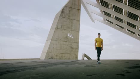 retrato épico y primer plano de un joven y atractivo hombre de moda patinando rápido bajo un panel solar en un día soleado por la mañana con un fondo urbano en cámara lenta