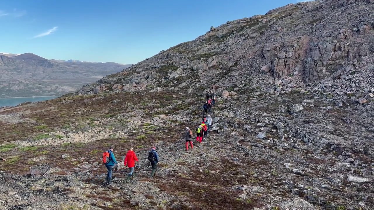 Un gruppo di turisti scala la collina sull'isola di Immikkeertikajik. Scoresbysund, Groenlandia