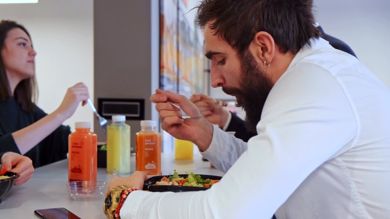 compañeros de trabajo sonriendo mientras comen almuerzo en la cafetería de la oficina