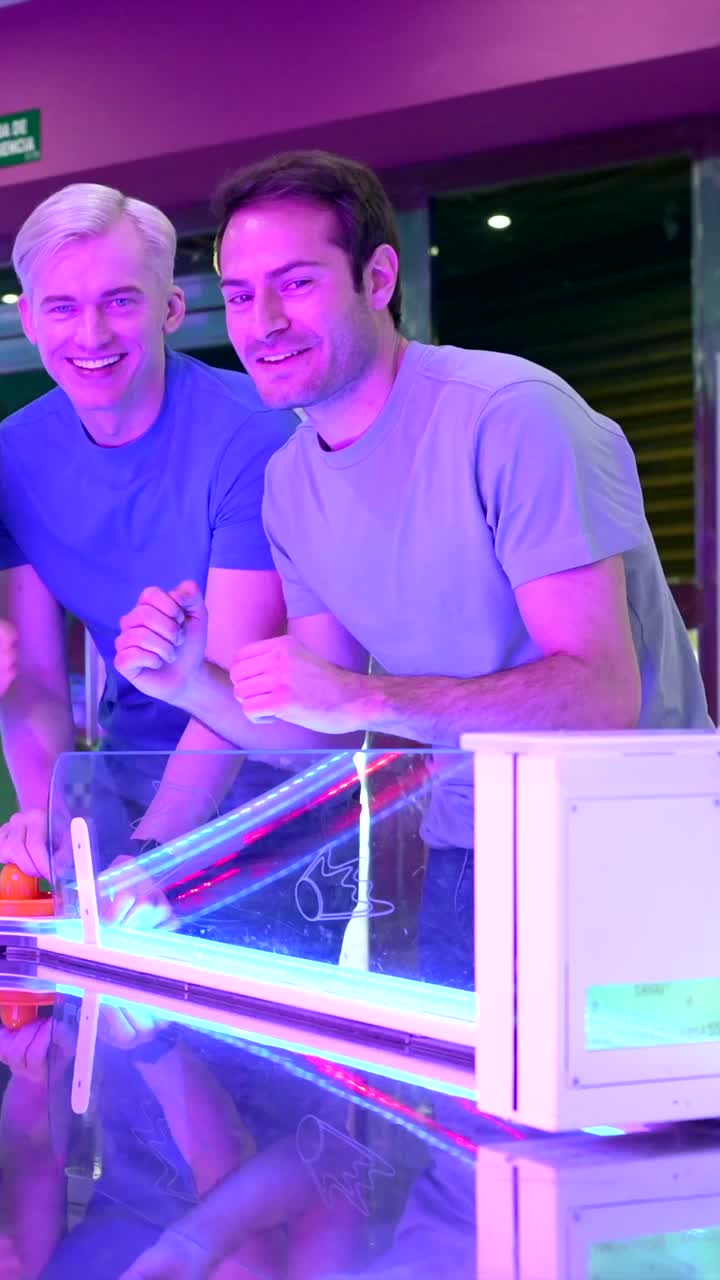 A group of people playing air hockey at an arcade