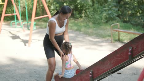 pregnant mother watching daughter play on slide at playground