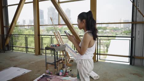 artist using phone while painting in an urban setting