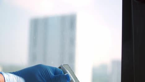 cleaning a window with a sponge and gloves