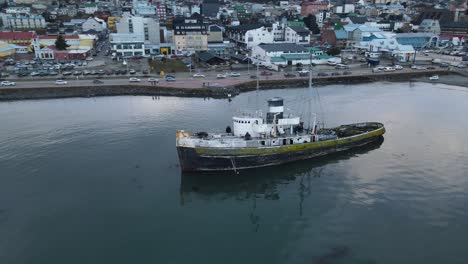 Vista-Aérea-De-Un-Barco-Varado-Con-Una-Ciudad-Al-Fondo