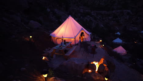 Mujer-Saliendo-De-Una-Tienda-De-Campaña-Iluminada-En-Una-Zona-De-Glamping,-Paisaje-De-Utah,-EE.-UU.