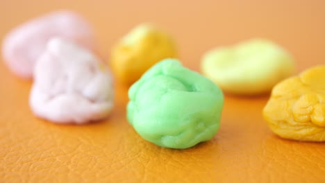 close-up of colorful chewing gum pieces on an orange surface