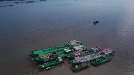 Toma-Aérea-De-Grúa-Ascendente-De-Barcos-De-Trabajo-Anclados-Cerca-De-La-Costa-En-Un-Día-Claro-Y-Soleado