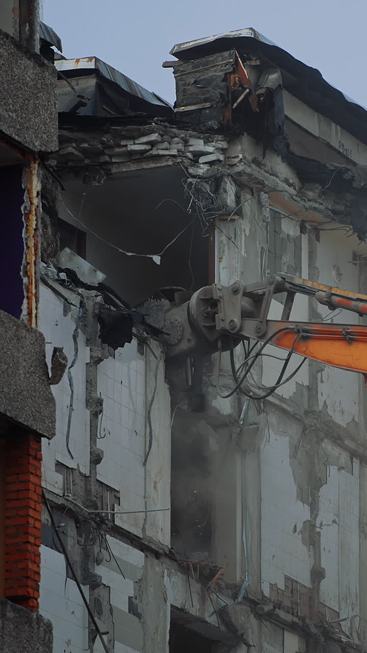 Destruction of the premises ruined by an earthquake. Demolishing equipment is breaking the upper floors. Dusty cloyds rise in the air. Vertical video