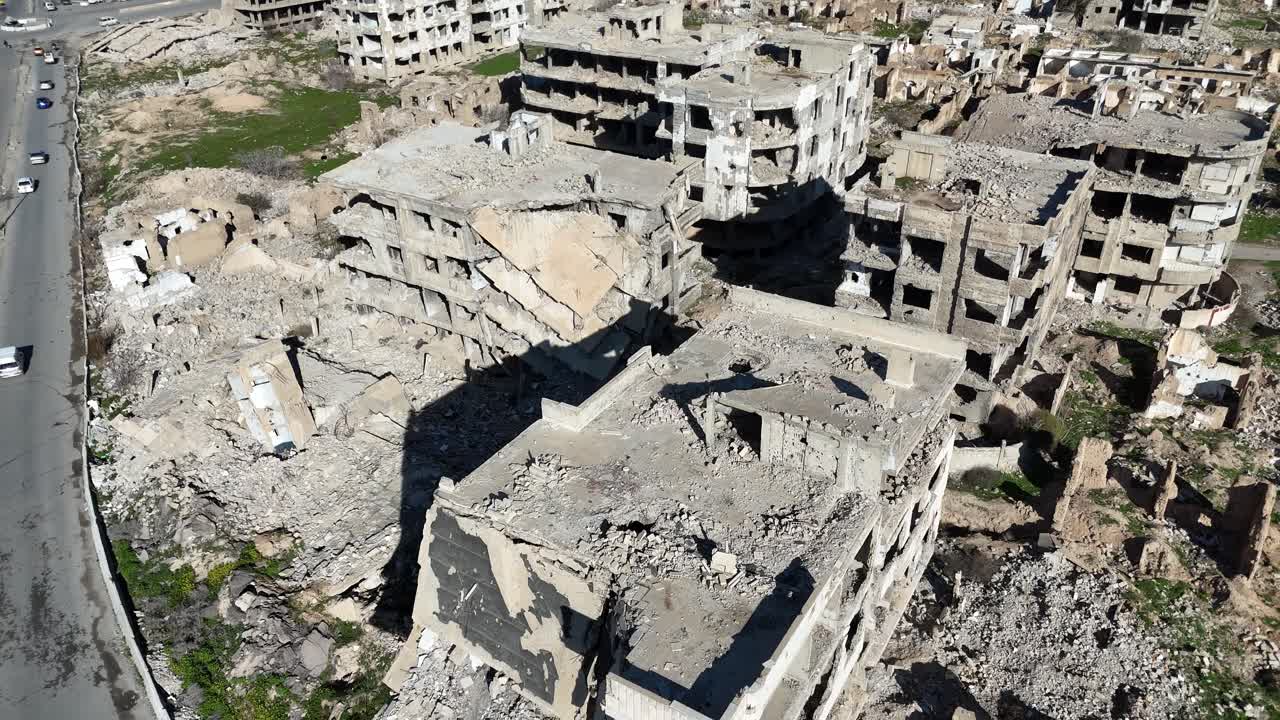 Ripresa aerea con drone che mostra edifici in rovina e macerie nel quartiere di Jobar a Damasco, documentando l'entità dei danni di guerra.