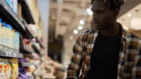 african american guy chooses products in the grocery store, put it to the cart