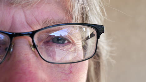 cierre el ojo de una anciana que se pone anteojos recetados después de hacerse un examen en el optometrista