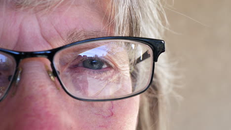 close up on the eye of an aging old woman putting on prescription glasses after getting an exam at the optometrist