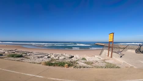 Seawall-along-the-Costa-da-Caparica-beach,-providing-protection-from-the-waves-and-creating-a-scenic-view-of-the-ocean