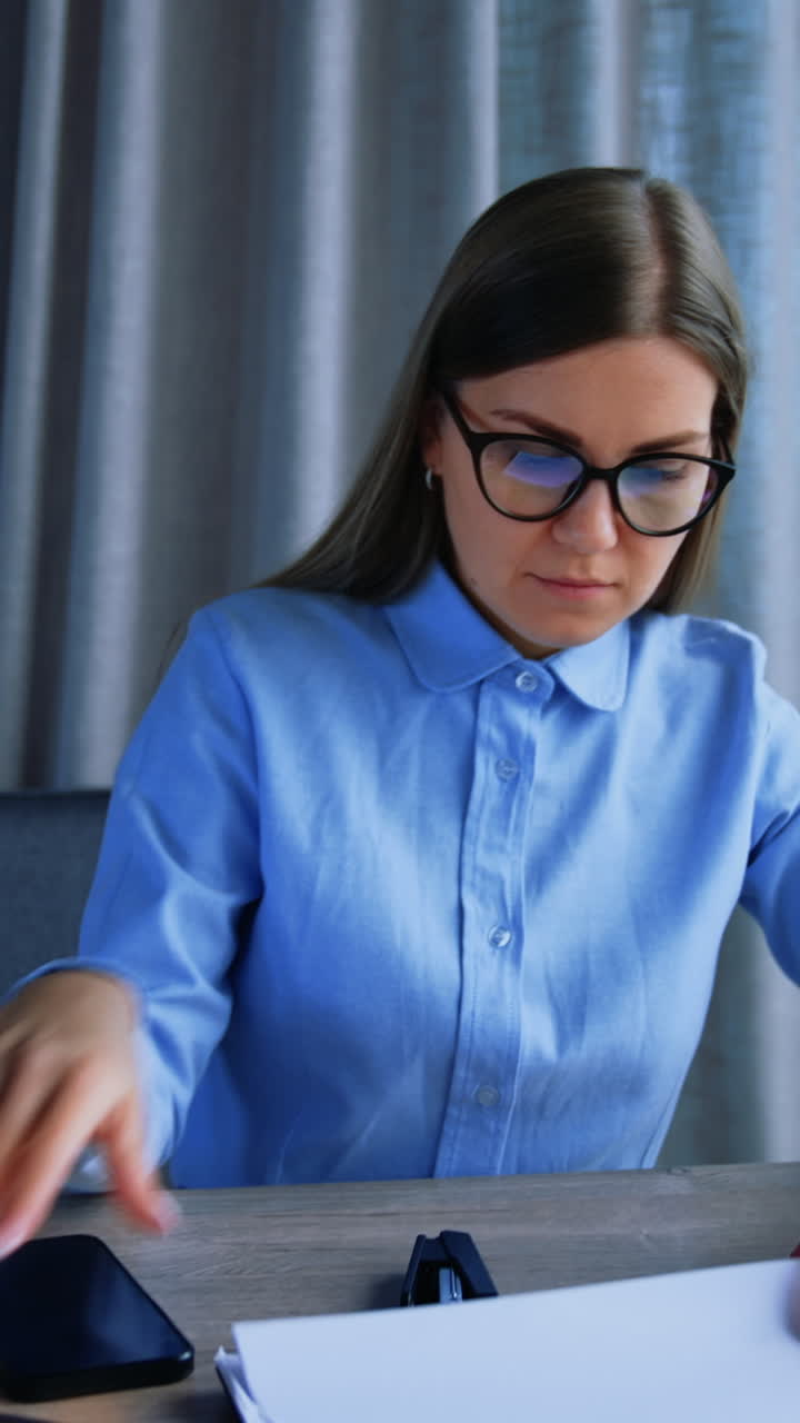 Blonde woman looking for a necessary document turning the pages. Busy business lady at work in the office. Vertical video