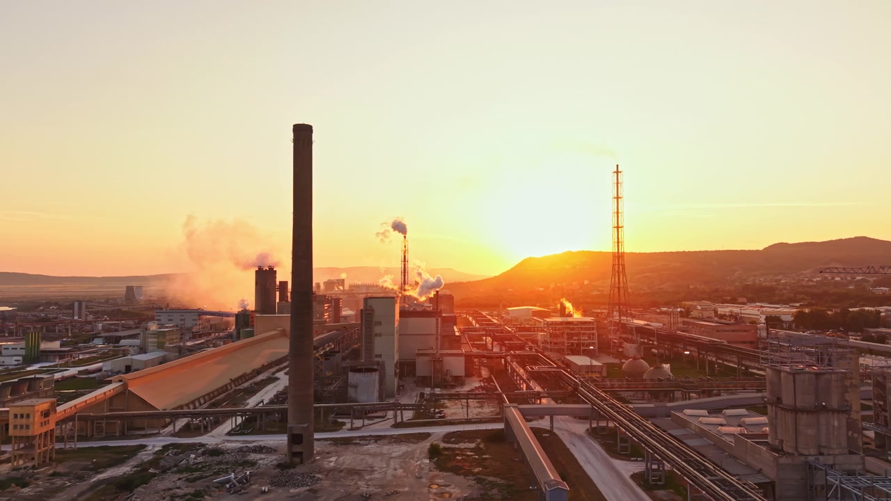 Pôr do Sol sobre Complexo Industrial com Chaminés e Edifícios de Produção