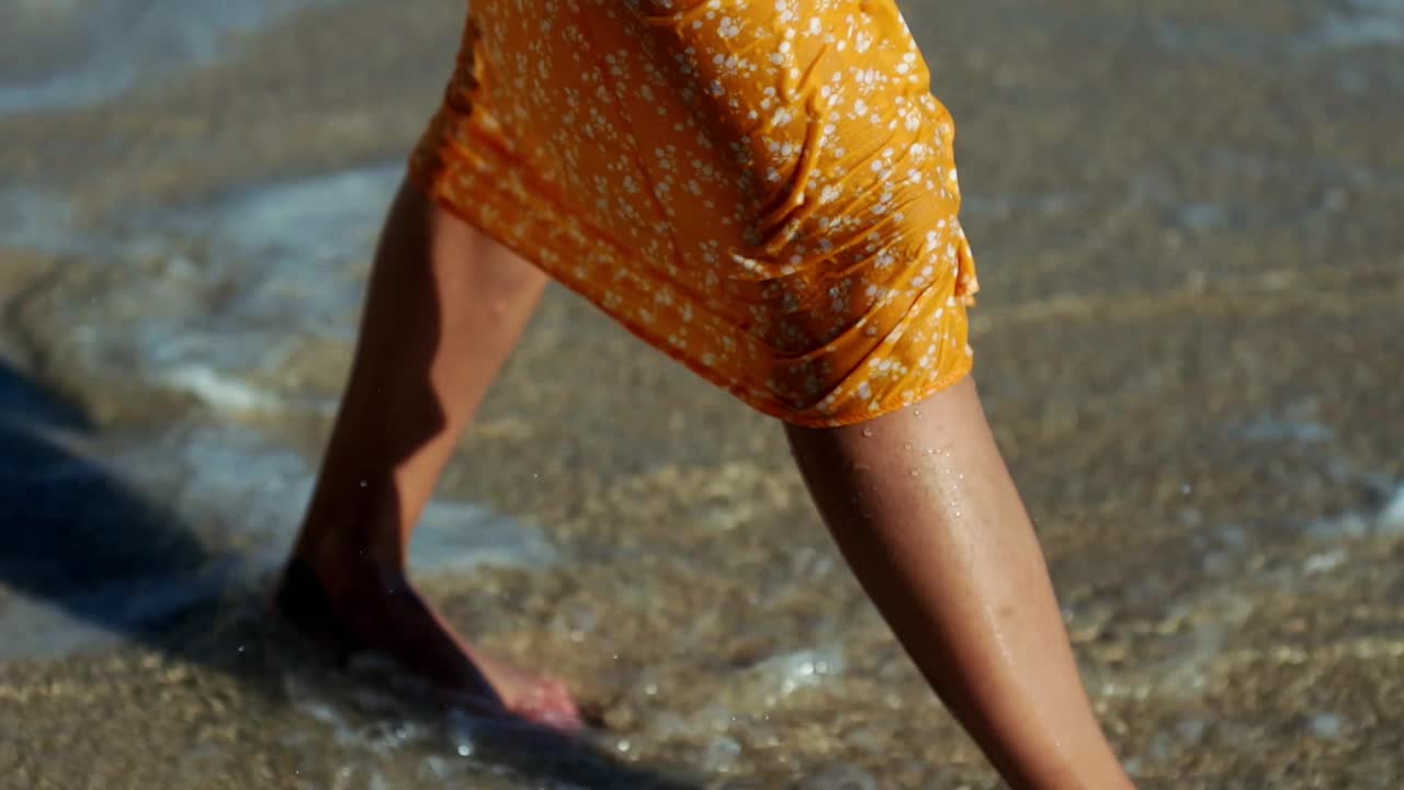 드레스를 입은 소녀가 해변에서 물 위를 걷는다