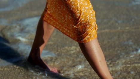 girl-in-a-dress-walks-through-the-water-on-the-beach