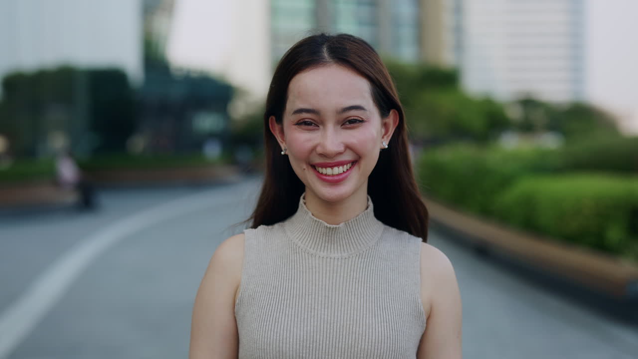 หญิงสาวชาวเอเชียกำลังยิ้มอย่างมีความสุขในสวนสาธารณะในเมือง