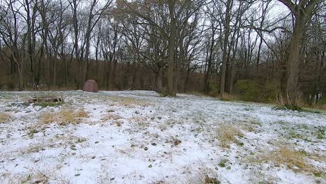 pov from the rear of off road vehicle atv while driving on a snow covered trail through the woods on an cloudy winter afternoon; the trail goes past a portable deer stand; point of view