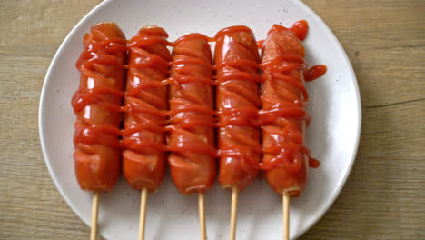 brocheta de salchicha frita con ketchup en plato blanco