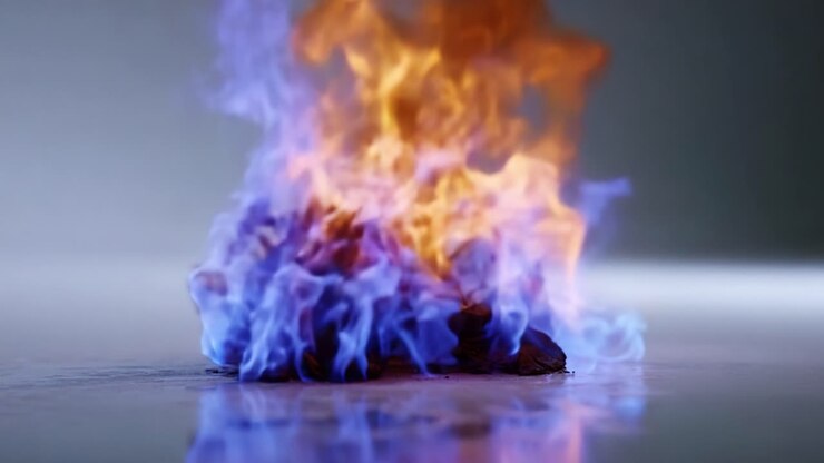 Levende flammer danser på en glat overflade og illustrerer den intense skønhed af ild i levende blå og orange farver, fanget i to frames fra en video