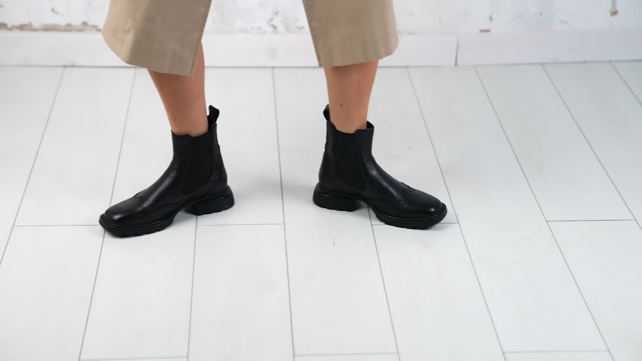 Funny dance in fashionable comfortable boots. Model moving in the studio to demonstrate stylish footwear. White backdrop.