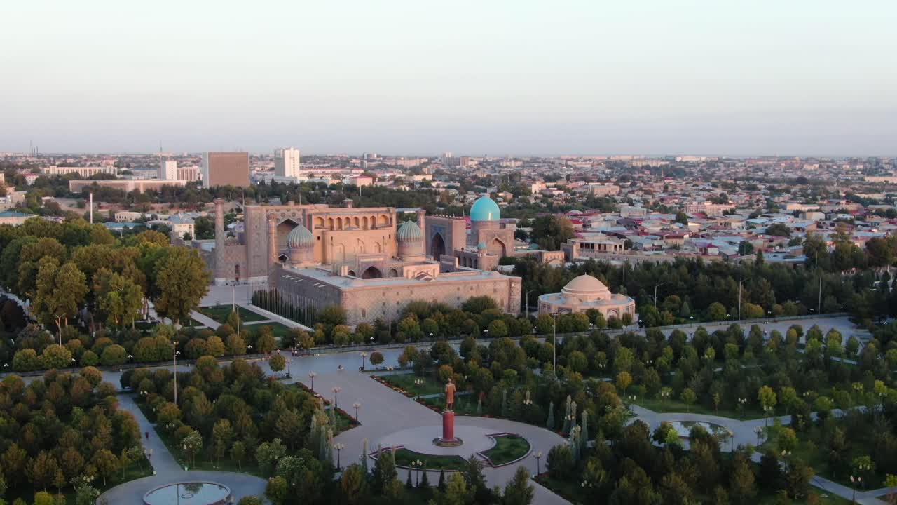 estatua conmemorativa de islam karimov con edificios de madrazas en la plaza pública de registan en samarcanda, uzbekistán