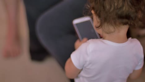 un niño pequeño toma un teléfono celular y comienza a presionar botones, haciendo que la pantalla se encienda