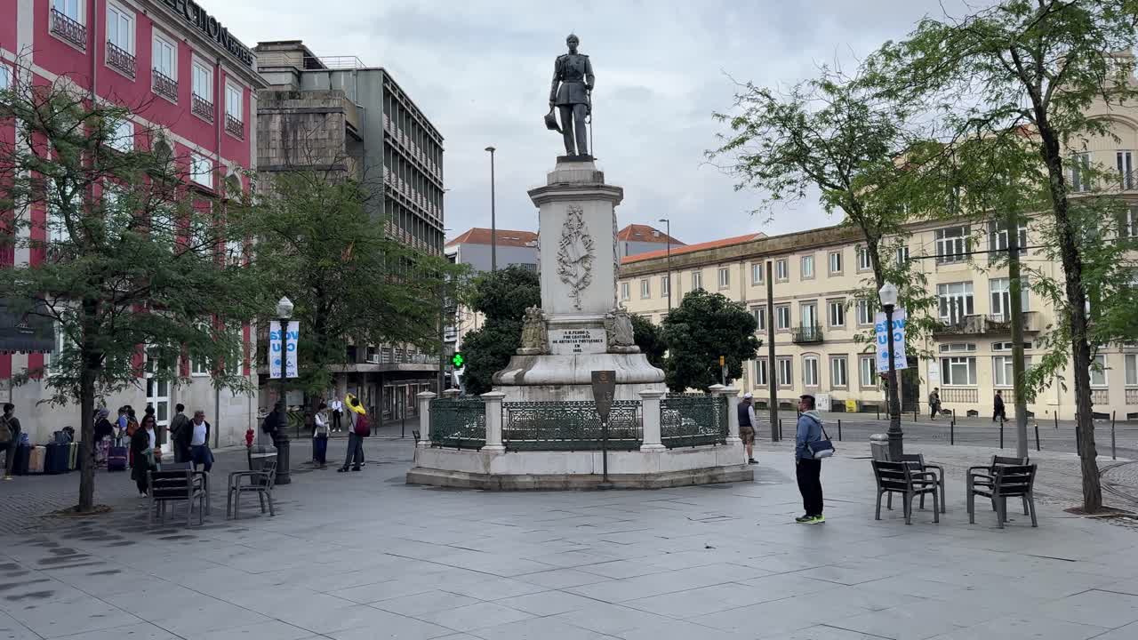 A view of a public square with a statue and buildings in a European city