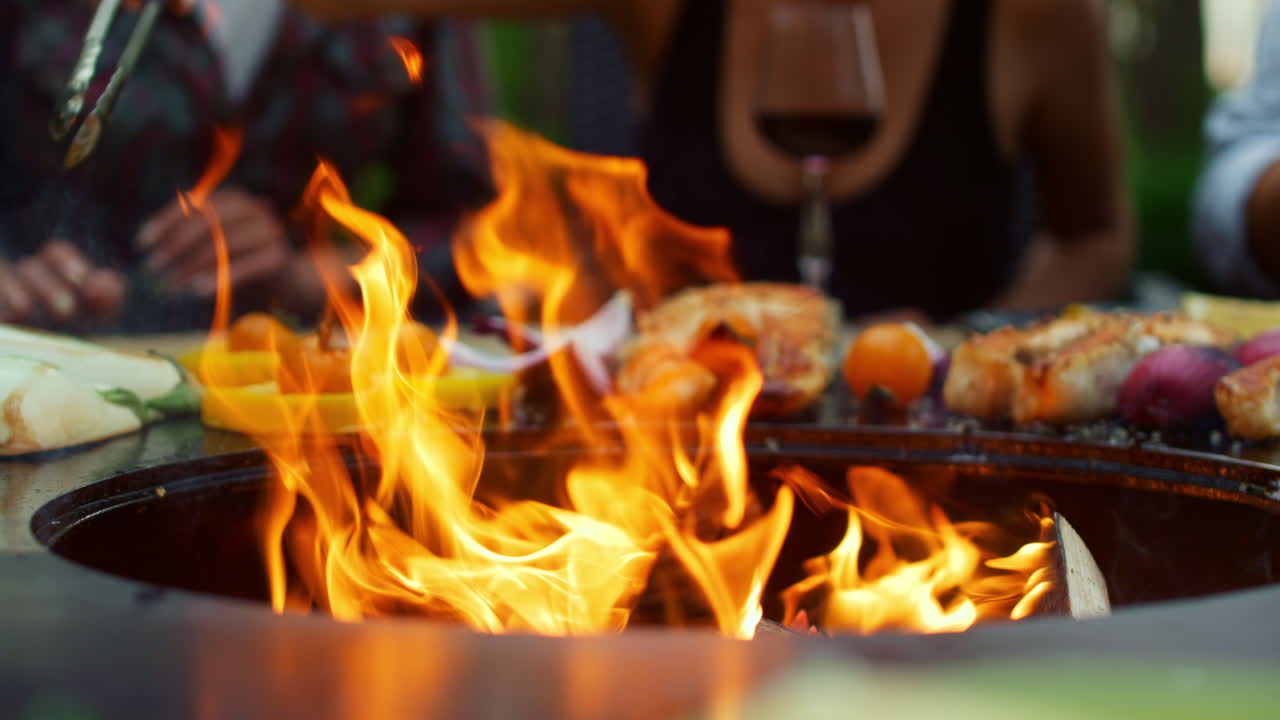 Primo piano di fiamme che bruciano nella griglia del barbecue in cortile. Verdure in cottura all'aperto.