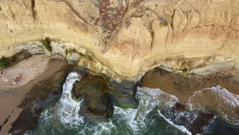 aerial top down, gentle waves crashing onto coastal sea cliffs in sunset cliffs, san diego