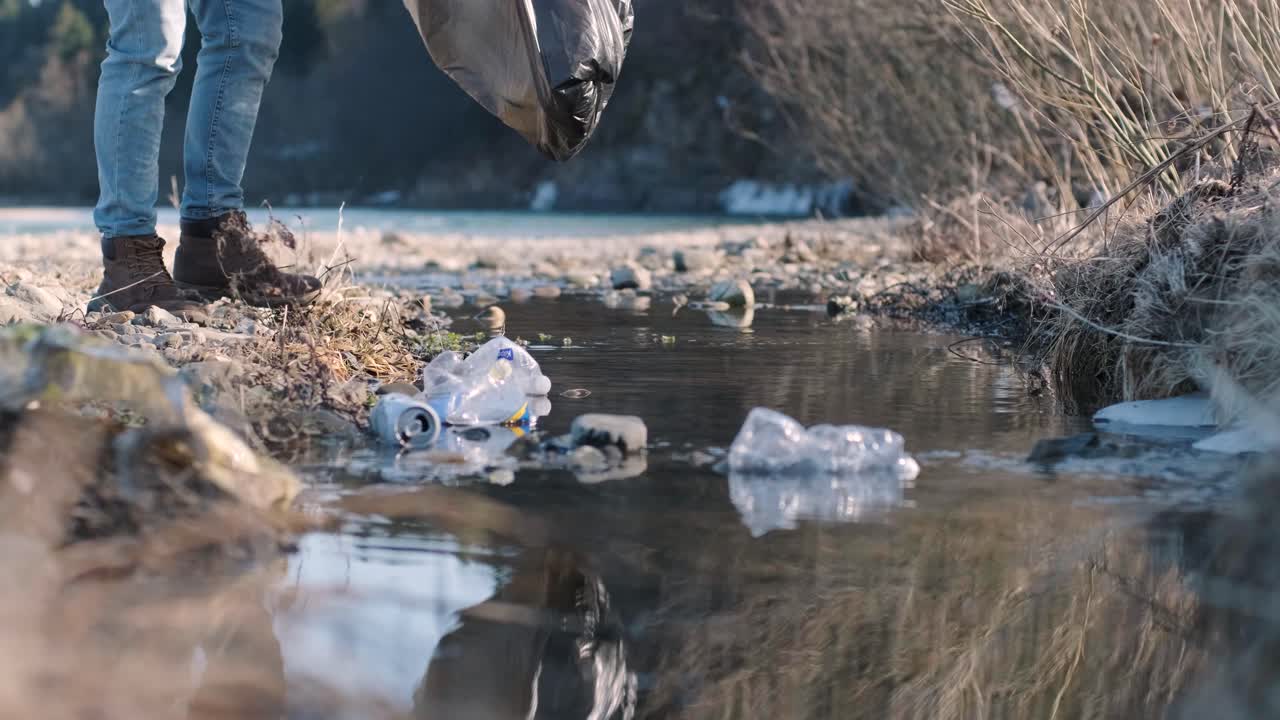 Teamwork cleaning plastic on the beach. Volunteers collect trash in a trash bag. Plastic pollution and environmental problem concept. Voluntary cleaning of nature from plastic. Greening the planet