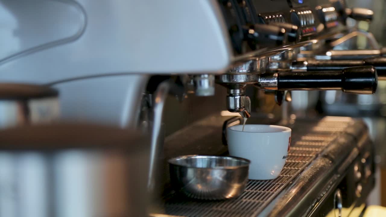 A close-up of an espresso machine pouring coffee into a white cup in a cozy café setting