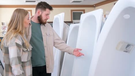 a young couple is choosing a new bathtub in a plumbing store with lots of plumbing fixtures. 4k