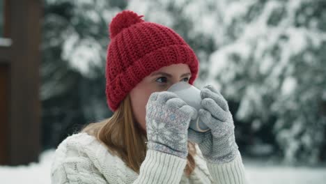 caucasian woman standing outdoors in winter and drinking hot tea