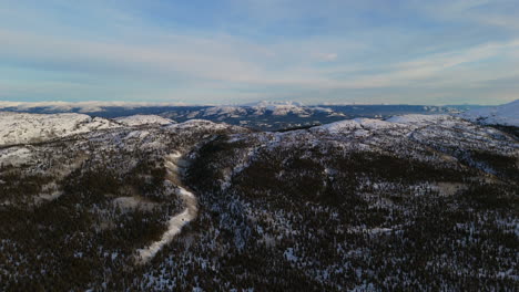 cinematic aerial shot of fish lake, whitehorse, yukon, showcasing a stunning winter landscape covered in snow. the vast frozen lake and surrounding mountains create a breathtaking winter wonderland.