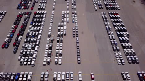 Aerial-view-of-logistics-concept-commercial-vehicles,-cars-and-pickup-trucks-waiting-to-be-load-on-to-a-roll-on-roll-off-car-carrier-ship-at-Laem-Chabang-dockyard