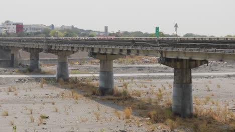 a long road bridge passing across a large dry river under an overcast summer sky in southern taiwan - medium wide shot