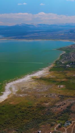 Azure skies reflecting in the beautiful calm waters of the lake. Bare mountains towering over the Mono Lake at backdrop of sky with white clouds. Vertical video