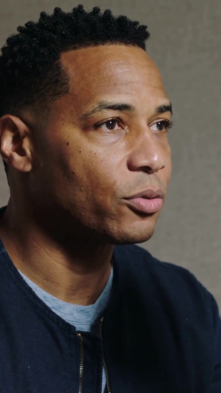 Vertical video: Answering question, man in navy jacket gesturing, pausing in podcast booth near mic