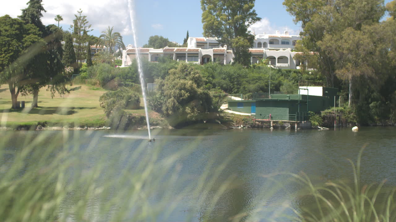 스페인 마르베야에 있는 골프 코스의 연못에서 슬로우 모션으로 물을 쏘는 분수의 영상