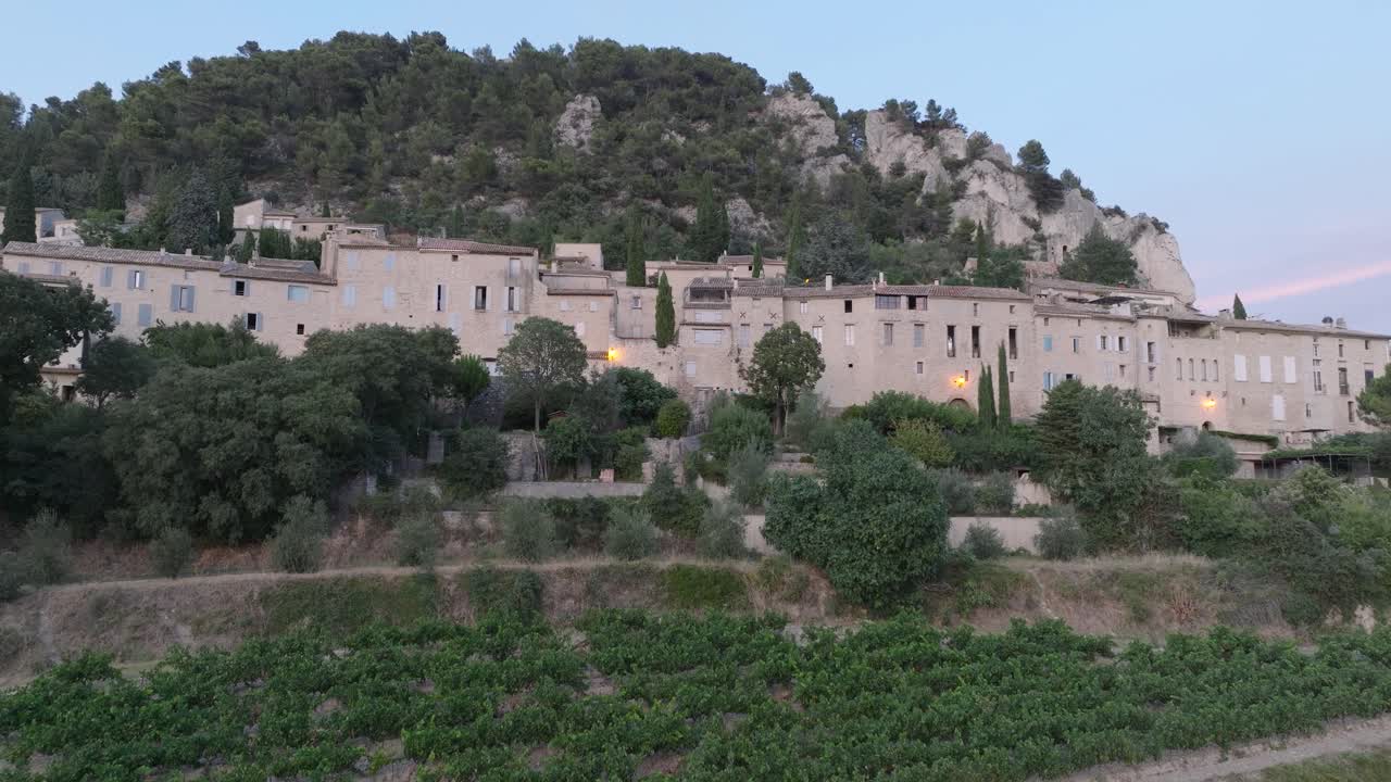Ripresa aerea con drone della città medievale di Séguret, Vaucluse, Provenza, con vigneti al tramonto in Francia