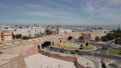 aerial-drone-video-with-downward-movement-of-land-gate-and-harbor-in-background-in-Cadiz,-Spain,-puertas-de-la-Tierra,-plaza-de-la-Constitucion