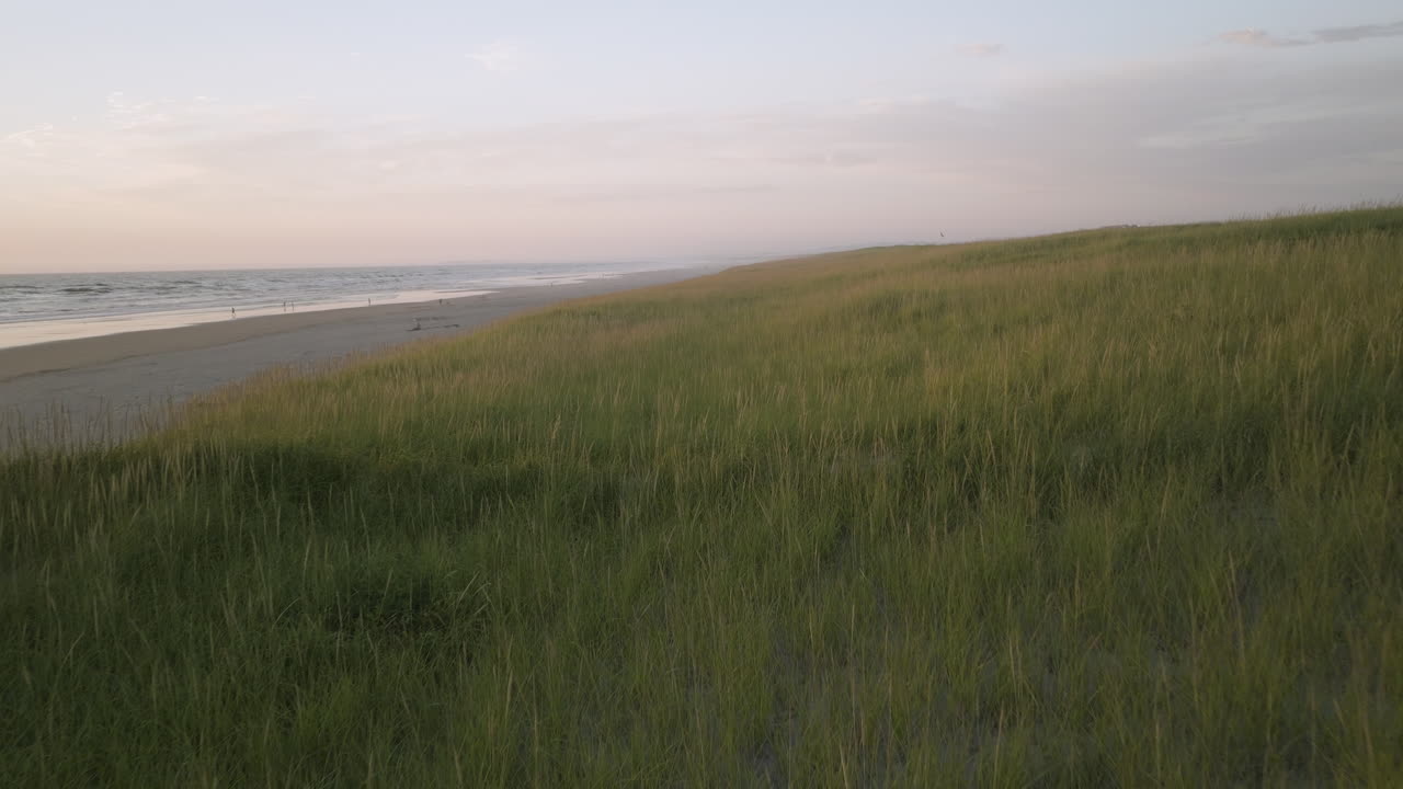 Saddle in grassland plains with beautiful yellow green glow of light over dunes above beach, single short path down to water
