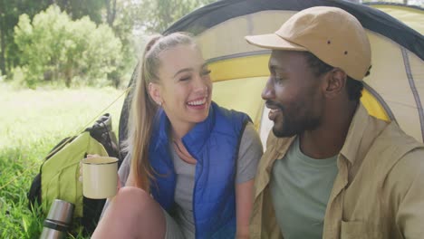 happy diverse couple camping and drinking tea in park, slow motion